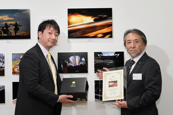 四輪部門グランプリ賞品 ニコン Z50 16-50 VR レンズキット 株式会社ニコンイメージングジャパン営業戦略部ゼネラルマネージャー松本淳さま（左）とJRPA小林会長（右）